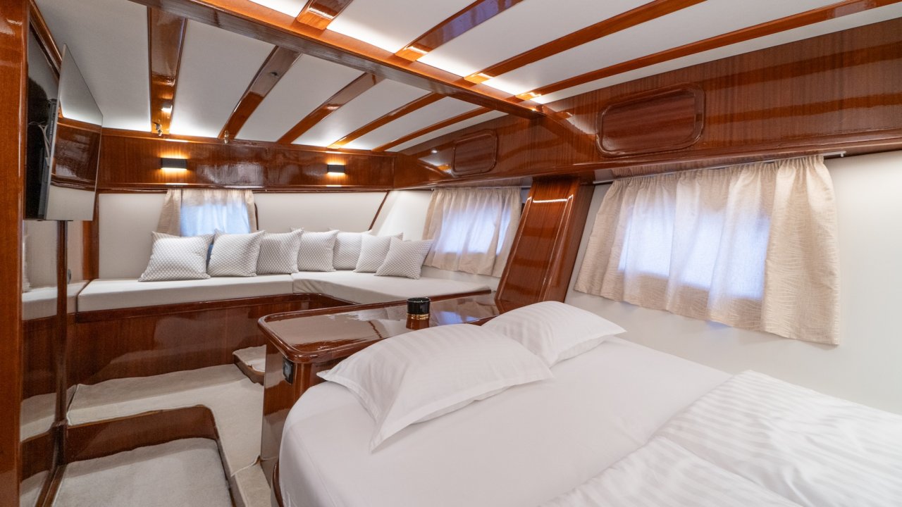 A yacht cabin with a cozy lounge area, wall-mounted TV, and wood paneling.