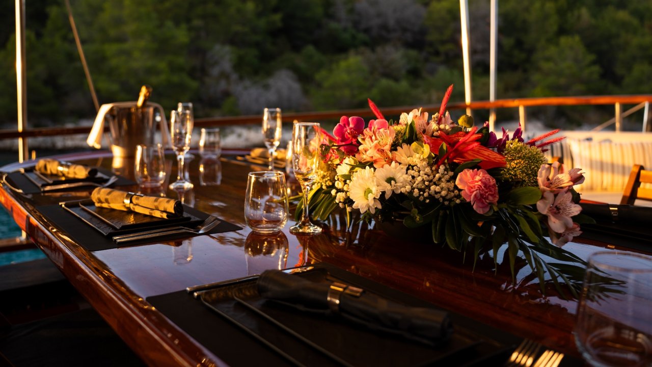 An outdoor dining table on a yacht set for dinner.