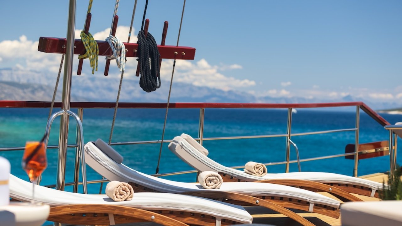 Three lounge chairs on the sun deck of a yacht, overlooking the blue Adriatic Sea.