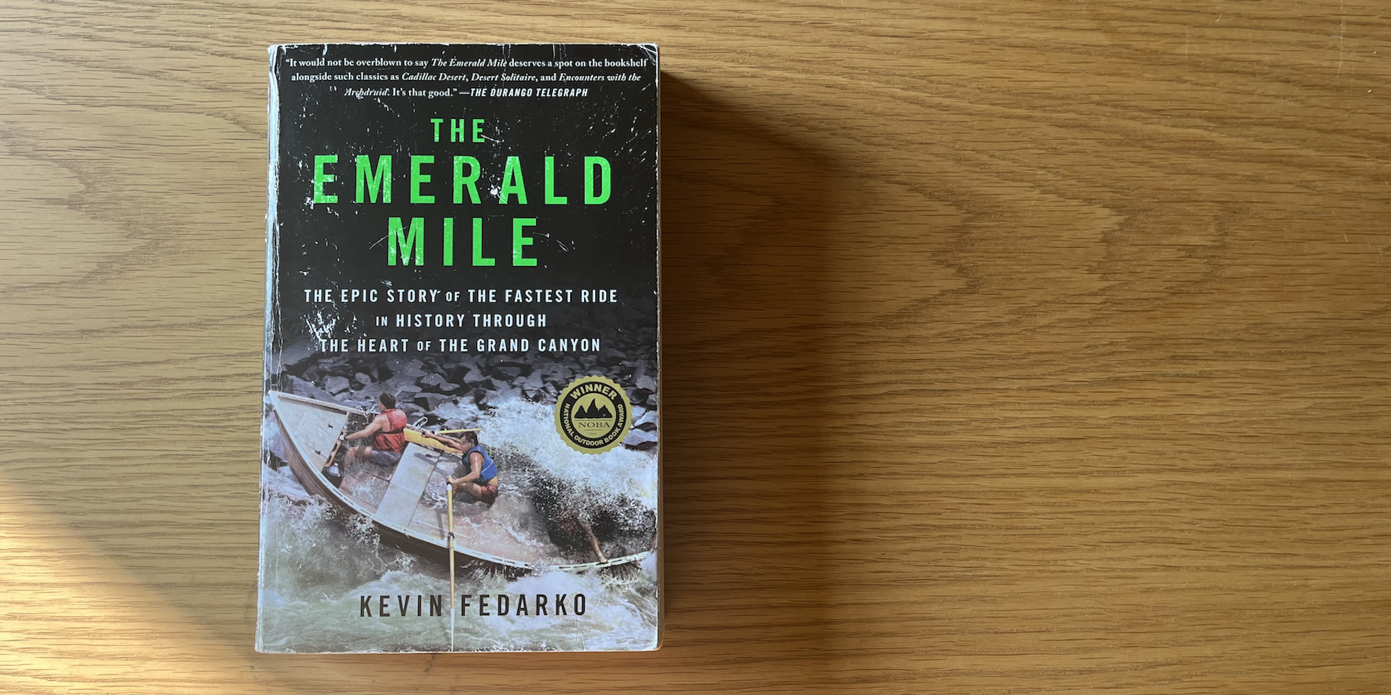 Copy of the book the Emerald Mile by Kevin Fedarko on a wooden table