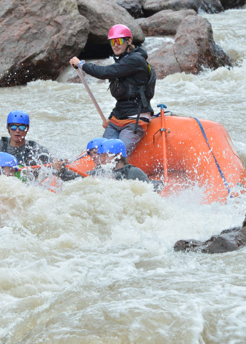 A river guide navigating a splashy rapid.